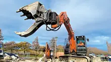 A man operating an excavator at a construction site with safety barriers installed around the work area.
